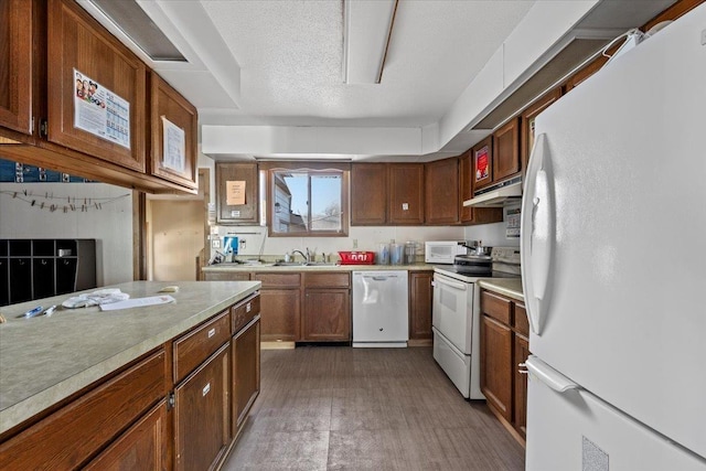 kitchen with a textured ceiling, white appliances, and sink