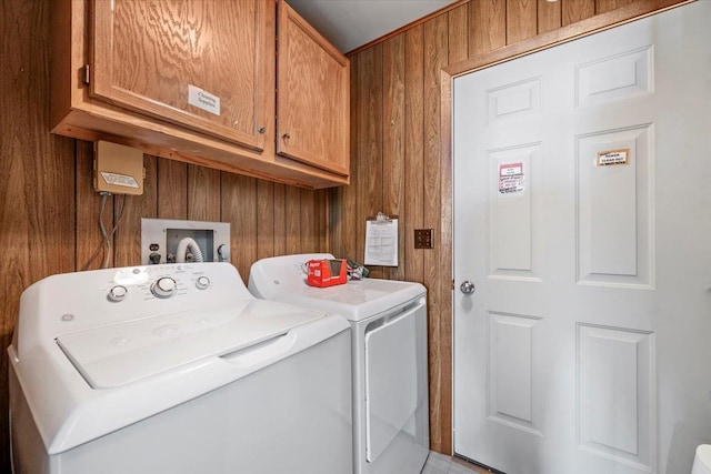 clothes washing area with separate washer and dryer and cabinets