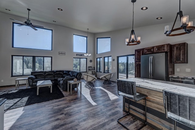 living room featuring a towering ceiling, ceiling fan, and dark wood-type flooring