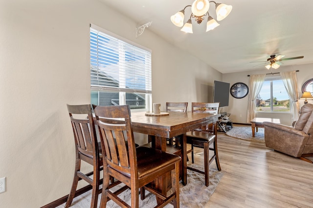 dining space featuring light hardwood / wood-style floors and ceiling fan with notable chandelier