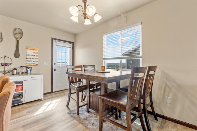 dining area with light wood-type flooring, an inviting chandelier, and plenty of natural light