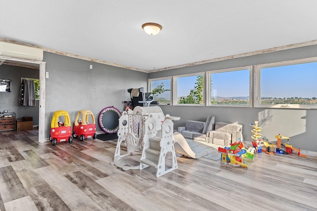 recreation room featuring light hardwood / wood-style floors and a wall mounted AC