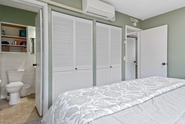 tiled bedroom featuring an AC wall unit, connected bathroom, and tile walls