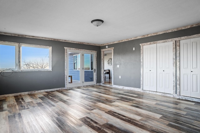 unfurnished bedroom with hardwood / wood-style flooring, access to exterior, and a textured ceiling