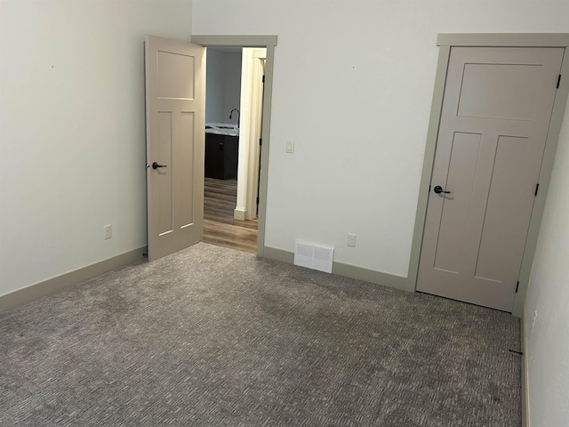 unfurnished bedroom with dark colored carpet and sink