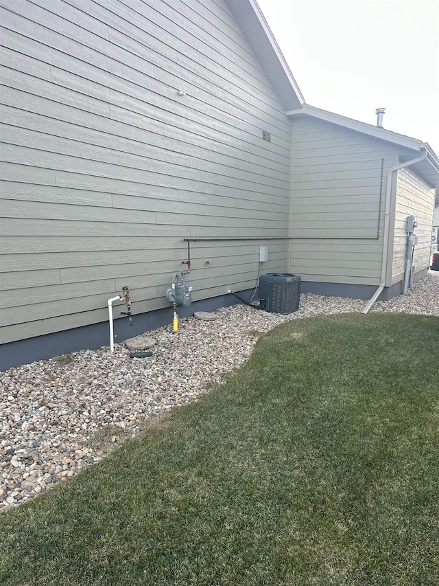 view of property exterior with central air condition unit and a yard