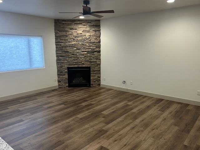 unfurnished living room with a fireplace, dark hardwood / wood-style flooring, and ceiling fan