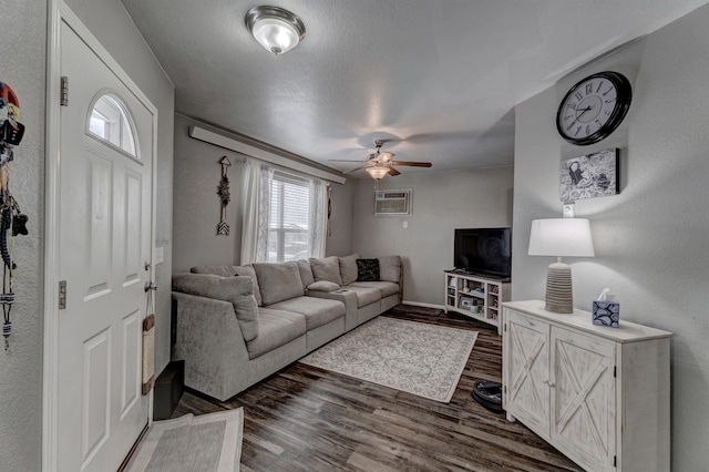 living room with a wall mounted air conditioner, ceiling fan, dark wood-type flooring, and a textured ceiling