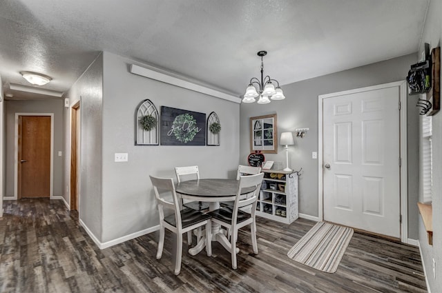 dining space featuring dark hardwood / wood-style floors, a textured ceiling, and an inviting chandelier