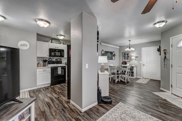 kitchen featuring black appliances, ceiling fan with notable chandelier, pendant lighting, and white cabinets