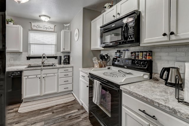 kitchen with light stone countertops, dark hardwood / wood-style flooring, sink, black appliances, and white cabinets