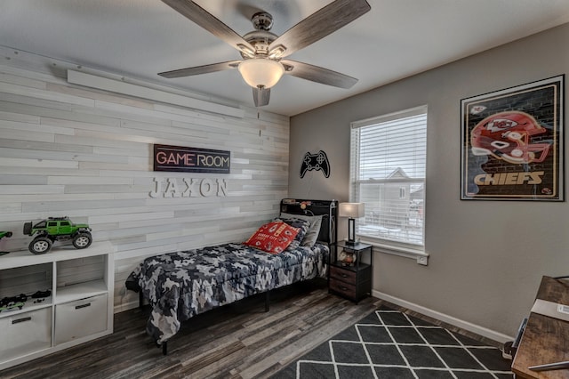 bedroom with ceiling fan, dark hardwood / wood-style flooring, and wood walls