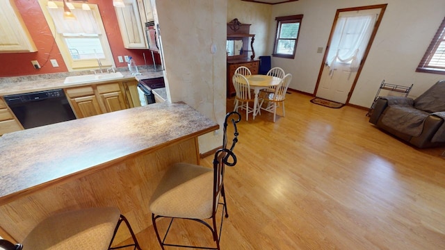 171 N Newton Ave, Hill City, SD 57745 - kitchen featuring a kitchen bar, range with electric cooktop, light brown cabinets, black dishwasher, and light hardwood / wood-style floors
