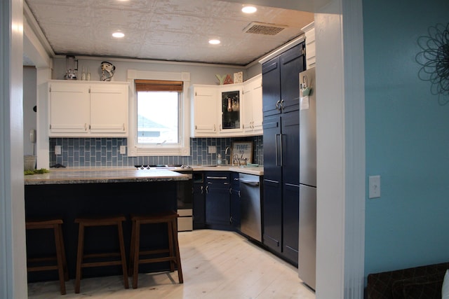 kitchen with white cabinets, dishwasher, kitchen peninsula, and tasteful backsplash