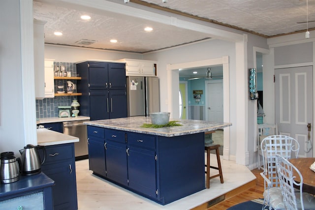 kitchen featuring white cabinets, a kitchen island, blue cabinets, and appliances with stainless steel finishes