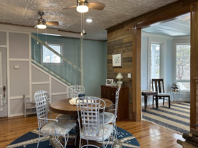 dining area featuring hardwood / wood-style flooring, crown molding, and wooden walls