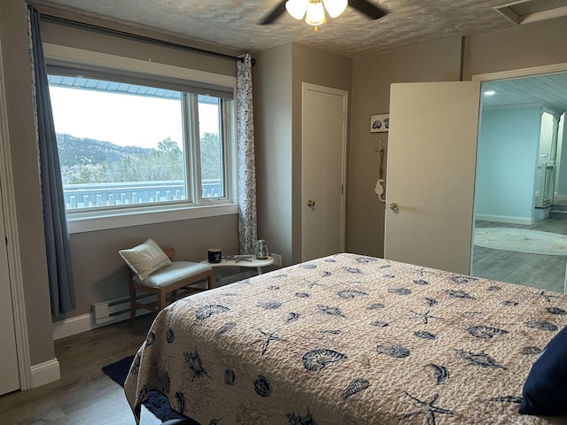 bedroom with hardwood / wood-style floors, ceiling fan, a textured ceiling, and a baseboard radiator