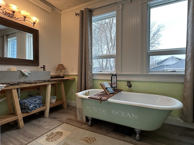 bathroom with hardwood / wood-style floors, crown molding, and a tub