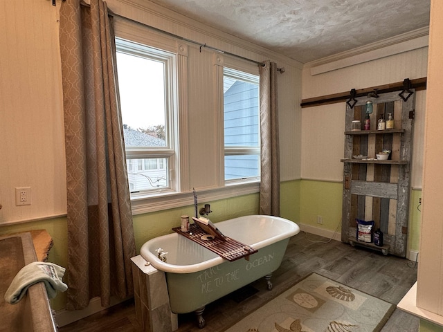 bathroom with hardwood / wood-style floors, a washtub, ornamental molding, and a textured ceiling