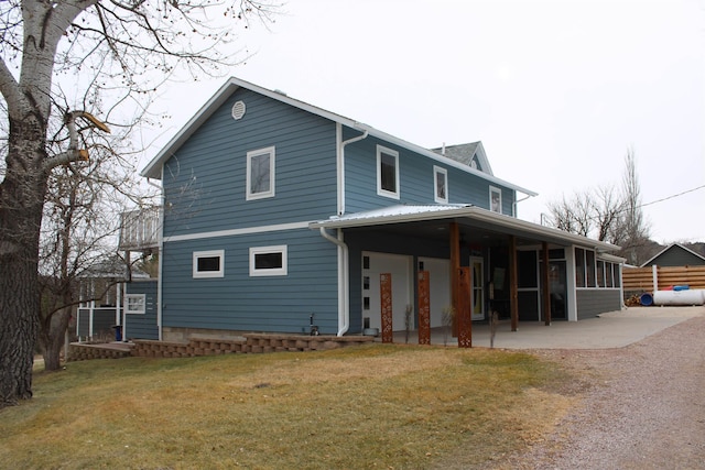 back of property with a yard, a patio, and a sunroom