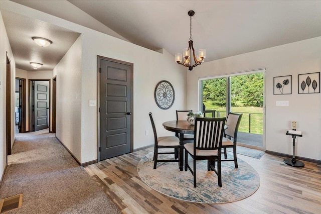 dining space with a textured ceiling, light hardwood / wood-style floors, an inviting chandelier, and lofted ceiling