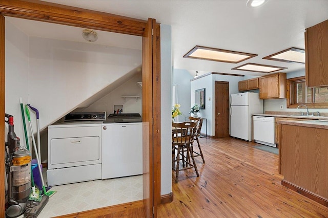 clothes washing area with washer and dryer, light hardwood / wood-style flooring, and sink