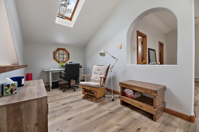 home office featuring light hardwood / wood-style floors and lofted ceiling with skylight