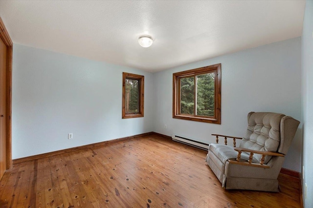 unfurnished room with a baseboard radiator and light hardwood / wood-style floors