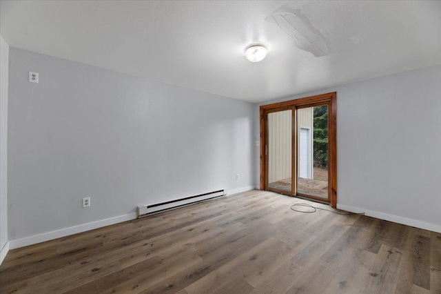 spare room featuring wood-type flooring and a baseboard radiator