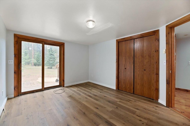 unfurnished bedroom with access to exterior, light hardwood / wood-style floors, and a closet