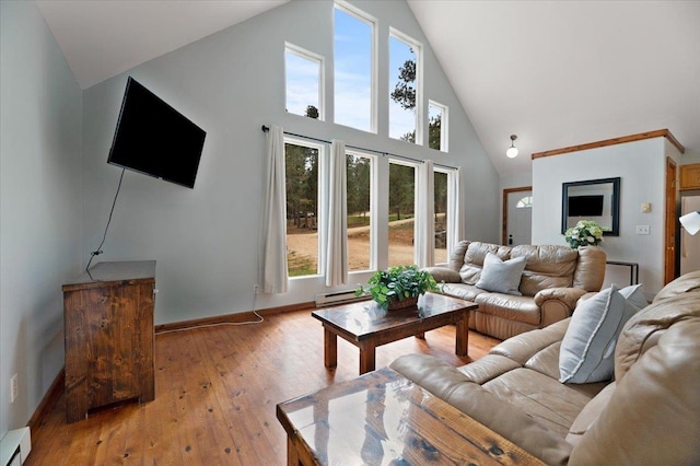 living room with a towering ceiling, light hardwood / wood-style flooring, and a baseboard heating unit