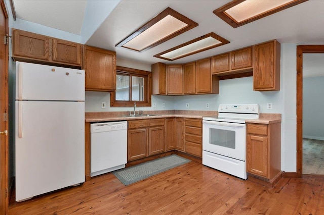 kitchen with sink, white appliances, and light hardwood / wood-style flooring