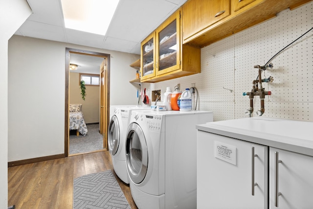 laundry area featuring cabinets, dark hardwood / wood-style flooring, washer and clothes dryer, and sink