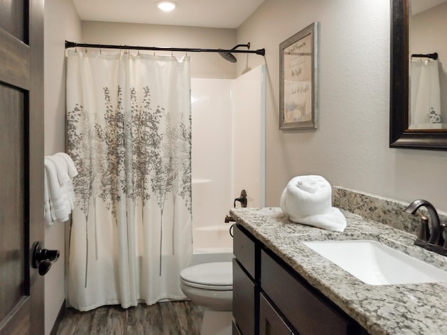 full bathroom featuring hardwood / wood-style flooring, vanity, toilet, and shower / tub combo