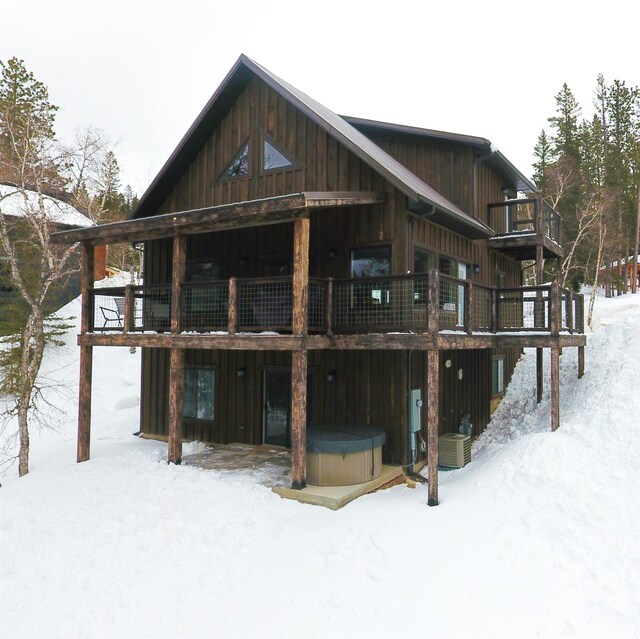 snow covered property featuring a balcony and a hot tub