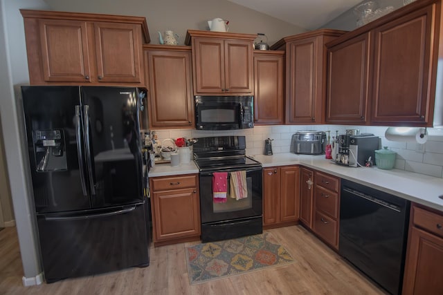 kitchen featuring decorative backsplash, black appliances, lofted ceiling, and light hardwood / wood-style floors