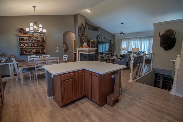 kitchen with pendant lighting, lofted ceiling, light hardwood / wood-style floors, a kitchen island, and ceiling fan with notable chandelier