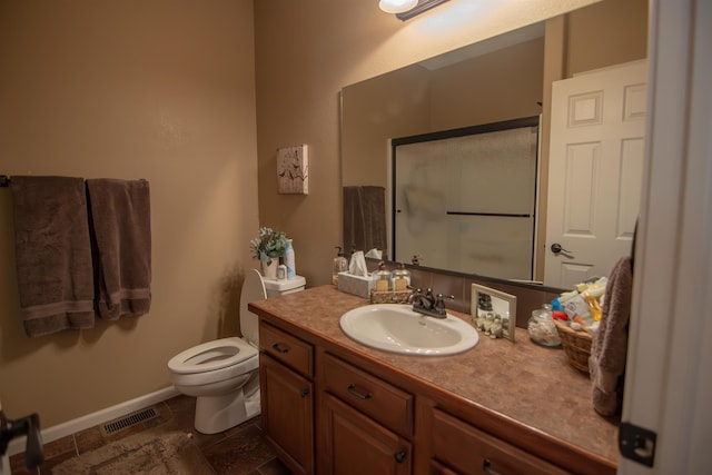 bathroom featuring vanity, a shower with shower door, and toilet