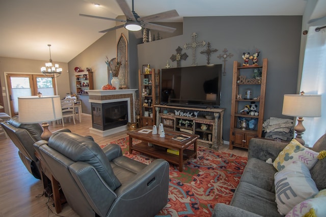 living room with ceiling fan with notable chandelier, light wood-type flooring, a multi sided fireplace, and lofted ceiling