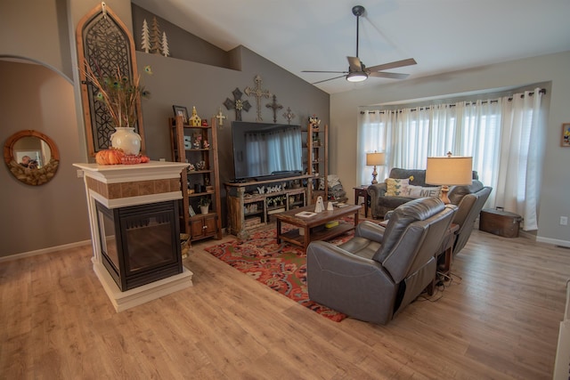 living room with a multi sided fireplace, light hardwood / wood-style floors, vaulted ceiling, and ceiling fan