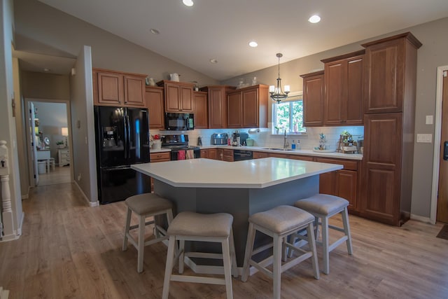 kitchen featuring a center island, backsplash, black appliances, sink, and vaulted ceiling