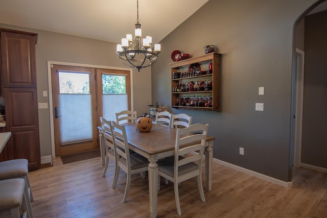 dining space with vaulted ceiling, an inviting chandelier, and light hardwood / wood-style flooring