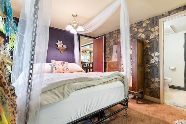 carpeted bedroom featuring a notable chandelier and connected bathroom