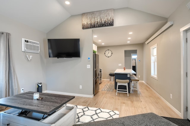 interior space with a wall mounted AC, lofted ceiling, and light wood-type flooring