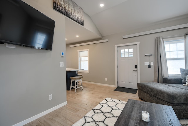 foyer entrance with light hardwood / wood-style floors and vaulted ceiling