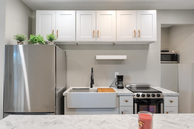 kitchen featuring white cabinetry, sink, light stone counters, and appliances with stainless steel finishes