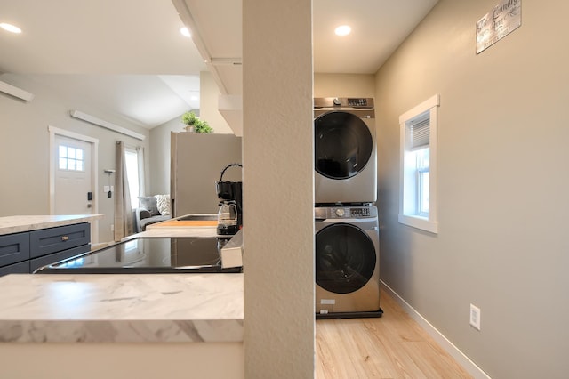 washroom featuring stacked washer and dryer and light hardwood / wood-style flooring