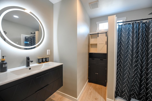 bathroom with hardwood / wood-style floors, vanity, and walk in shower