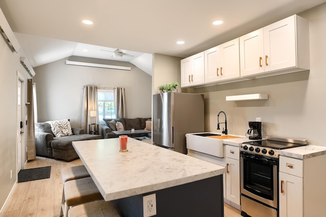 kitchen featuring white cabinets, appliances with stainless steel finishes, lofted ceiling, and sink