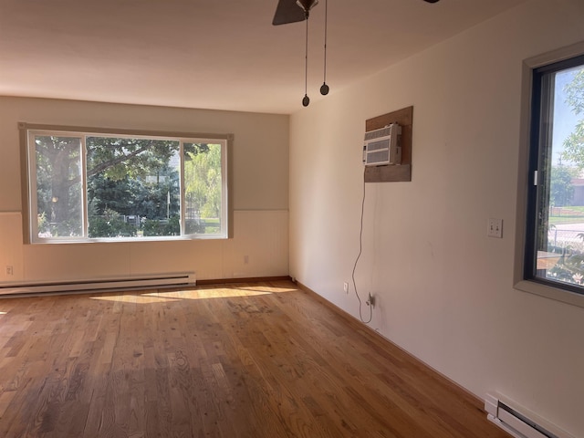 empty room featuring a wall mounted air conditioner, wood-type flooring, and a baseboard radiator